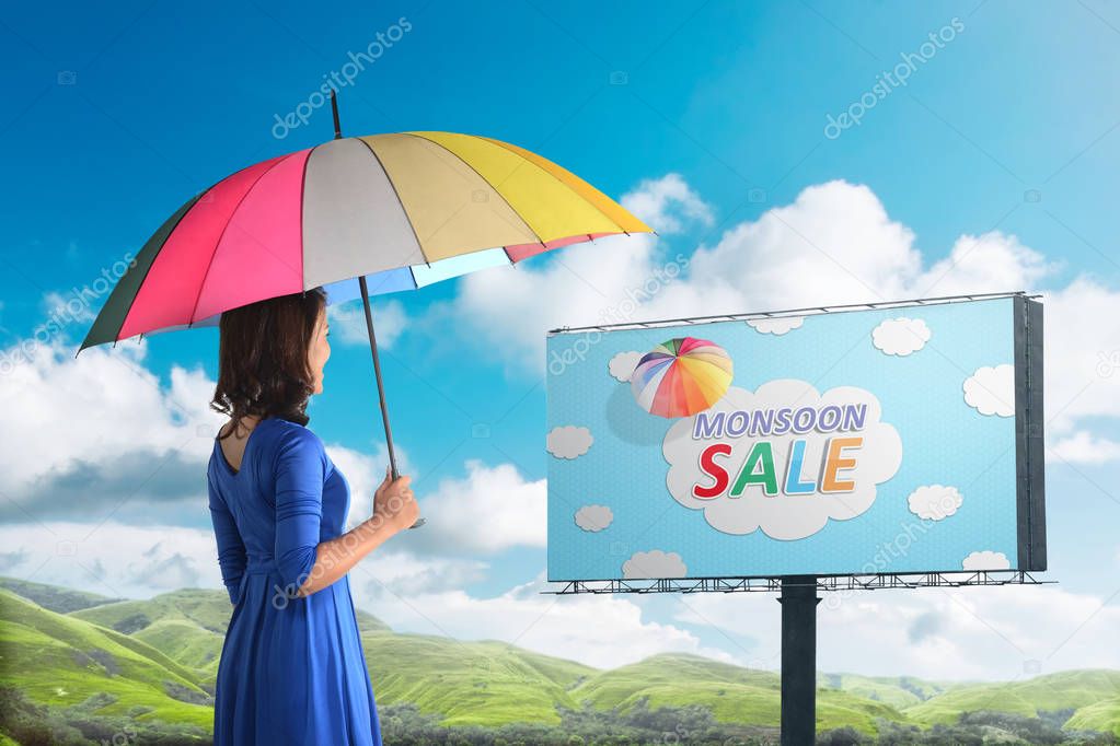 Happy asian woman looking at monsoon sale sign on billboard. Monsoon sale concept