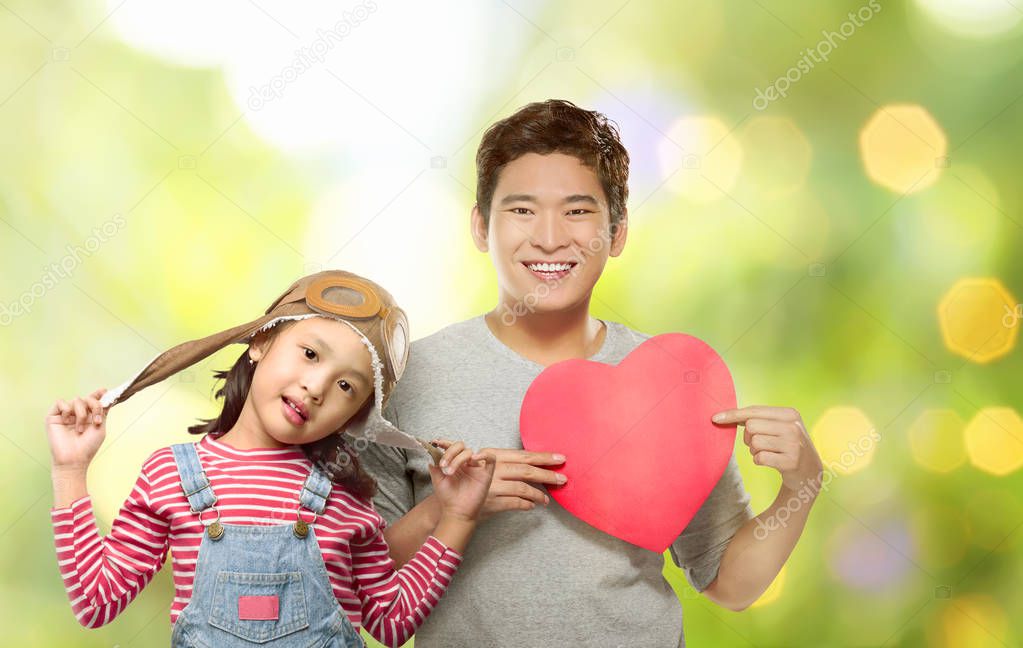 Happy asian daughter and her father holding red heart with blur background