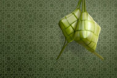 Ketupat geleneksel bayram kutlaması için yeşil arka plan üzerinde besindir