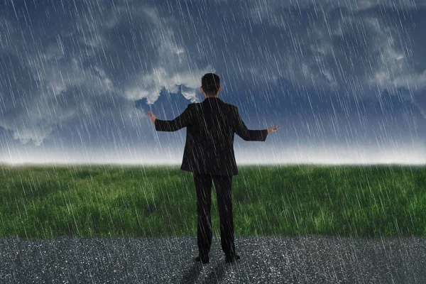 暗い空を背景に雨の中に立っているアジア系のビジネスマンの背面図 — ストック写真