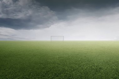 Yeşil futbol sahası bulutlu karanlık gökyüzü altında 