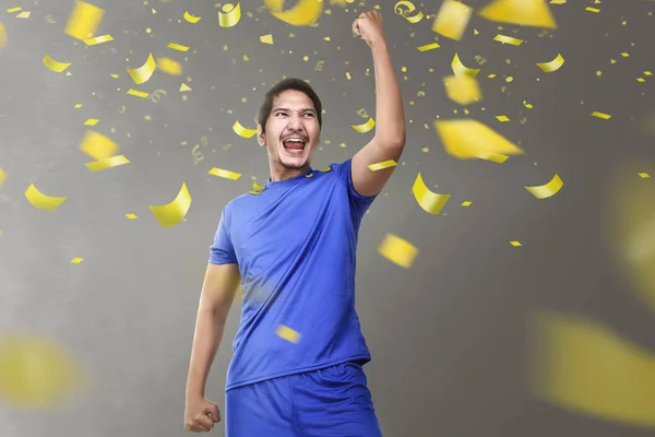 asian soccer player man celebrating victory with falling confetti