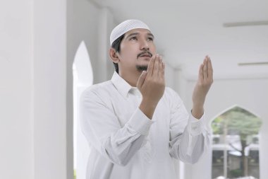 Genç Asyalı Müslüman adam Tanrı'ya camide dua