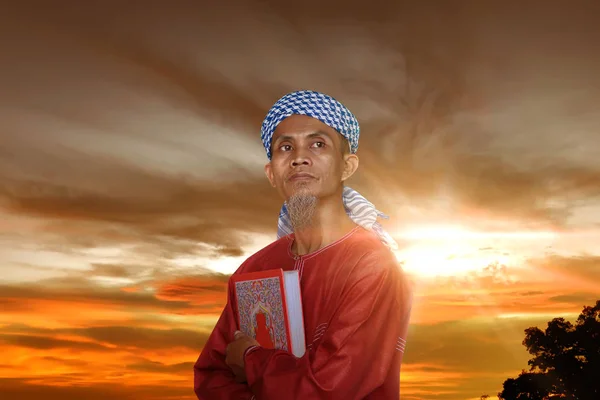 老亚洲穆斯林人与古兰经在日落天空 — 图库照片