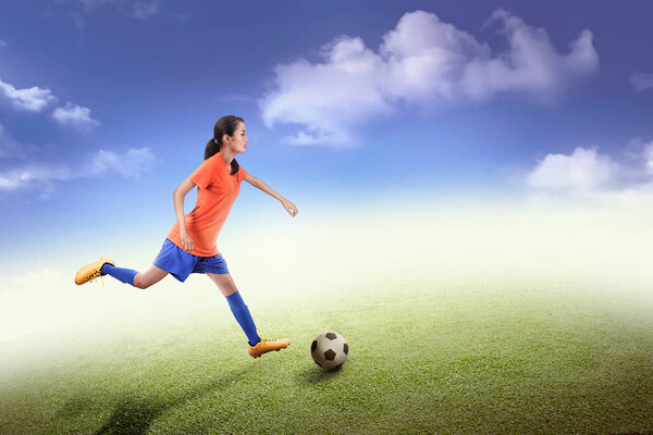 Side view of asian soccer player woman in action on field