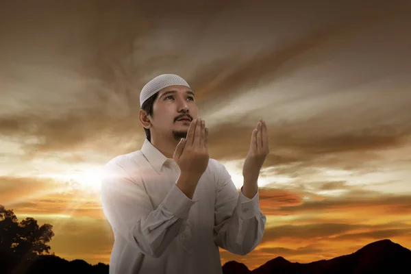 asian muslim man praying to god at sunset