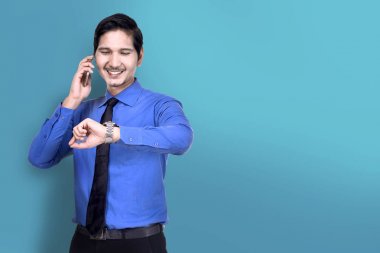 Mavi arka plan üzerinde telefonla konuşurken izle Asya işadamı onay gülümseyen