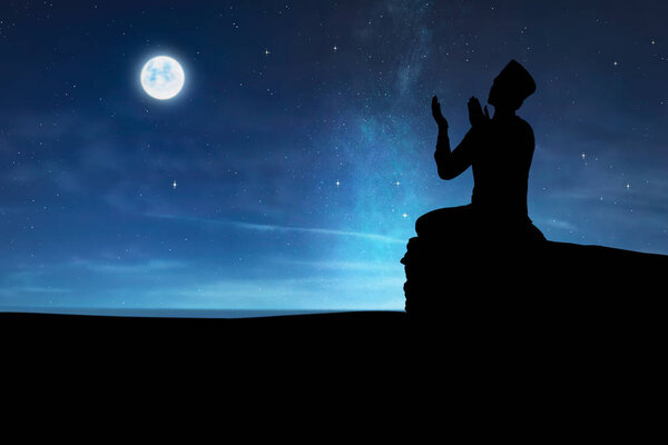 Silhouette of muslim man praying to god at night