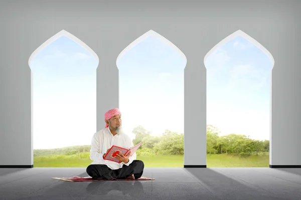 高级亚洲穆斯林男子坐在清真寺内的可兰经 — 图库照片