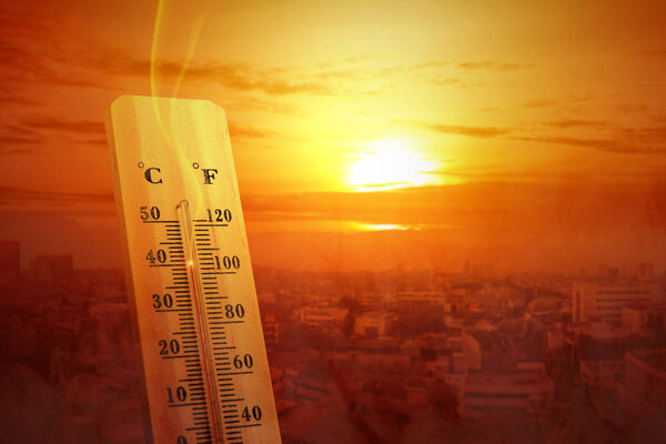 Thermometer with high temperature on the city with glowing sun b