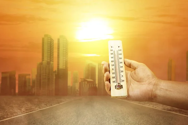 Hand holding thermometer with high temperature on the city with — Stock Photo, Image