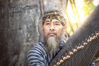 Kecapi tutan Asyalı yaşlı bir adam.