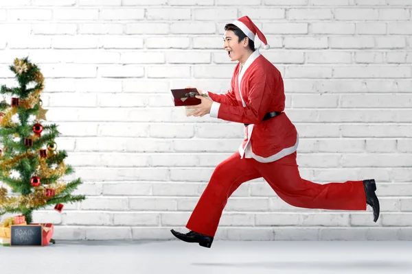 Ασιάτης με κοστούμι Σάντα τρέχει ενώ κρατώντας το κουτί δώρων wi — Φωτογραφία Αρχείου