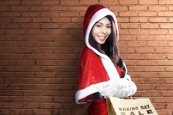 Asiatische Frau im Weihnachtsmann-Kostüm mit Einkaufstaschen mit Boxen — Stockfoto