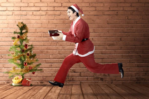 Aziatische man in Santa kostuum draait terwijl het houden van de geschenkdoos wi — Stockfoto
