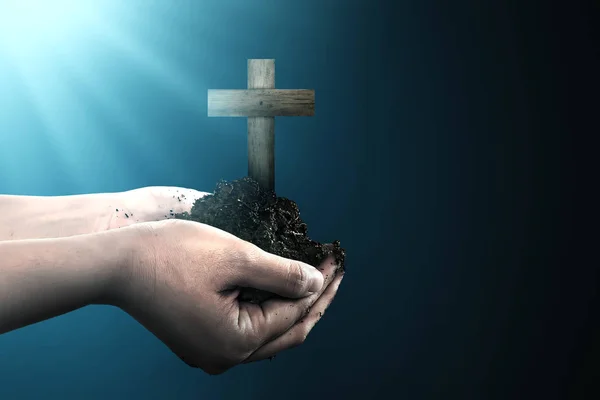 Human hand holding soil with Christian cross