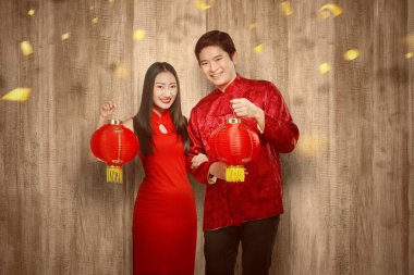 Cheongsam elbiseli Asyalı çift ellerinde Çin feneri tutuyor.