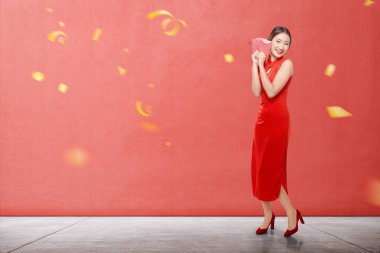 Cheongsam elbiseli Asyalı kadın elinde kırmızı zarflar tutuyor.
