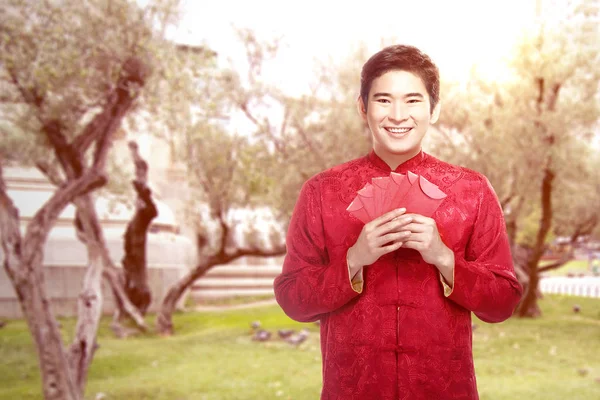 Un homme chinois asiatique dans une robe cheongsam tenant des enveloppes rouges — Photo