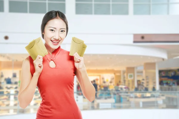 Mulher chinesa asiática em um vestido cheongsam segurando envelopes vermelhos — Fotografia de Stock