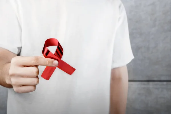 Man in a white shirt showing a red ribbon — Stock Photo, Image