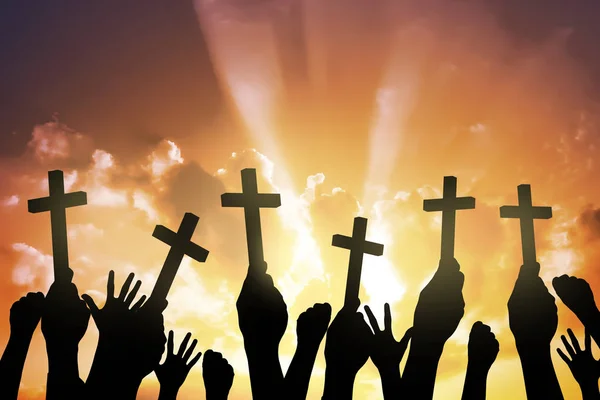 Silhouette of people holding Christian cross — Stockfoto