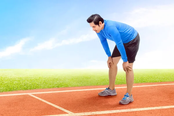 Asiatischer Läufer legt nach Lauf auf der Laufstrecke eine Pause ein — Stockfoto