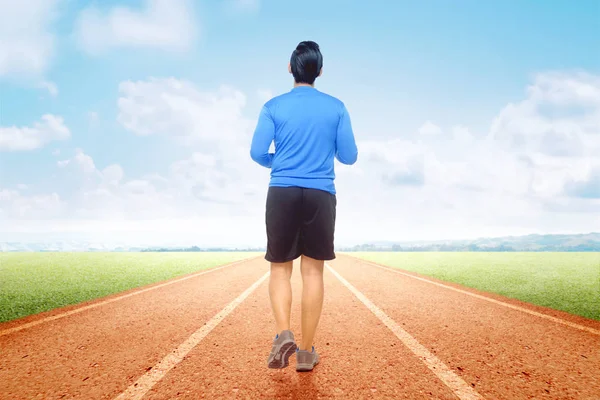 Rear view of Asian runner man running on the running track