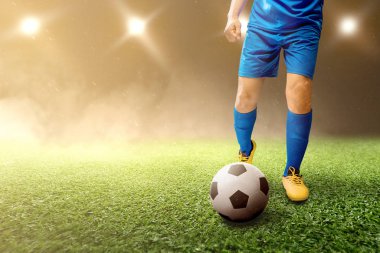 Futbolcu adam futbol sahasında topa vuruyor. 