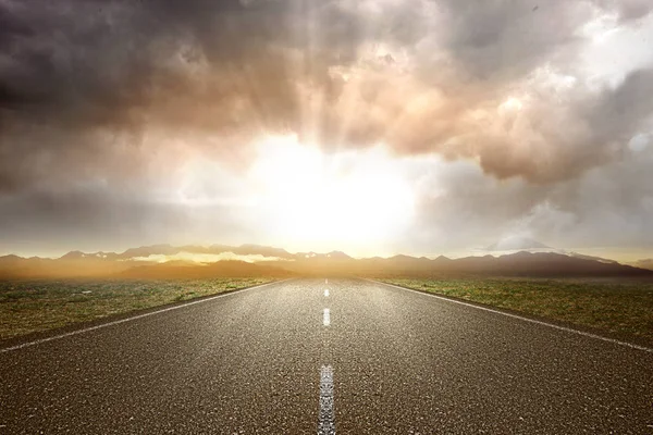 Yeşil çimenli ve dağ manzaralı asfalt yol 