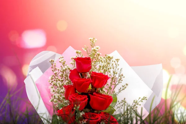 Red roses bouquet wrapped in paper with blurred light background — Stockfoto