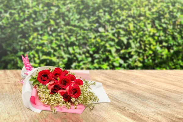 Ramo de rosas rojas envueltas en papel con una cinta rosa en una lana —  Fotos de Stock