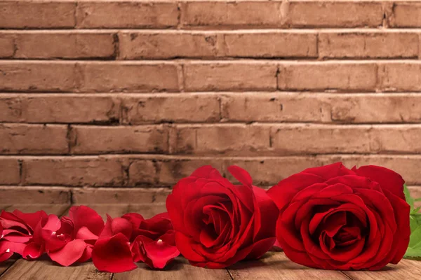 Rode rozen en rozenblaadjes op een houten tafel — Stockfoto