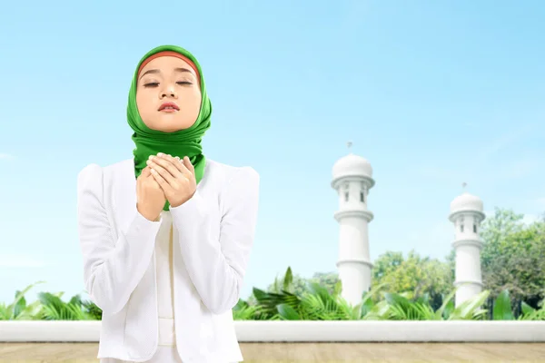 立ち上がりながら手を上げ モスクのテラスで祈りながらベールに身を包んだアジア系ムスリム女性 — ストック写真
