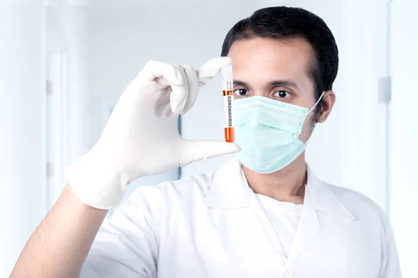 Asian doctor man in flu mask and protective gloves holding a test tube with a coronavirus blood sample. Prevent flu disease Coronavirus