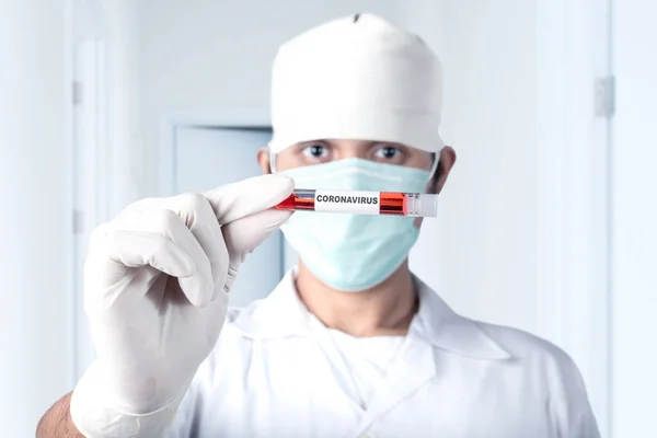 Asian doctor man in flu mask and protective gloves holding a test tube with a coronavirus blood sample. Prevent flu disease Coronavirus