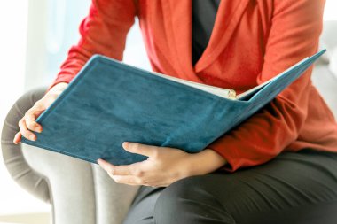 İş kadını, elinde kitapla işyerinde oturuyor.