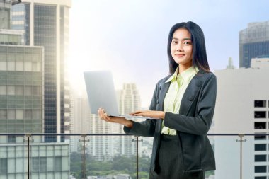 Asyalı iş kadını iş yerinde dizüstü bilgisayar kullanırken ayakta duruyor