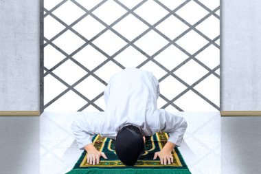 Cami içinde namaz kılan Asyalı Müslüman bir adam.