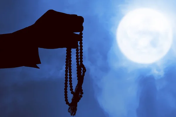 穆斯林男子的轮廓 双手拿着祈祷珠在夜景背景下祈祷 — 图库照片