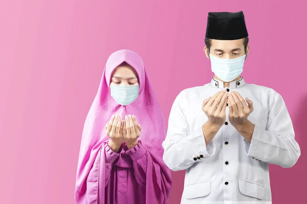 インフルエンザマスクをしたアジア系イスラム教徒のカップルが立ち上がり手を上げて一緒に祈る 広がるインフルエンザの病気を防ぐ コロナウイルス — ストック写真