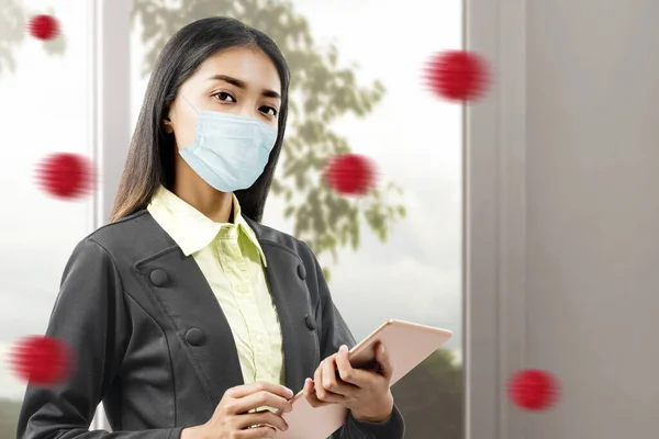 Asian businesswoman with flu mask standing while using a tablet. Prevent flu disease Coronavirus