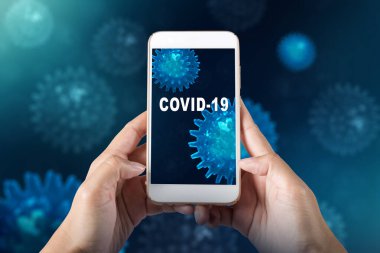Ekranda COVID-19 mesajı olan bir cep telefonu tutan eller. Grip hastalığını önle Coronavirus
