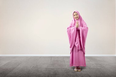 Duvak takmış Asyalı Müslüman kadın caminin içinde dua ediyor.