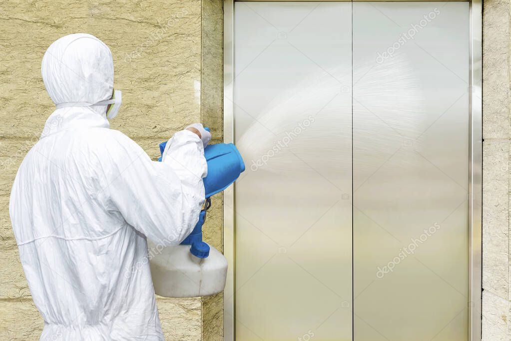 Man in a white protective suit spraying disinfectant in the office building. Prevent the spread flu disease Coronavirus