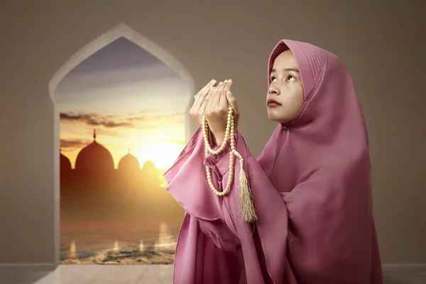 アジア系ムスリム女性のベールでの祈りのビーズで彼女の手にモスクのビューの背景 — ストック写真