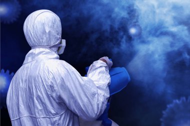 Beyaz koruyucu elbiseli bir adam havaya dezenfektan püskürtüyor. Grip salgını Coronavirüs 'ü önler.