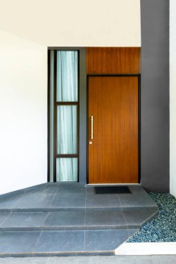 Modern bir evde pencere camı olan ahşap bir ön kapı.