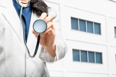 Hastanenin dışında steteskoplu doktor kadın bekliyor.