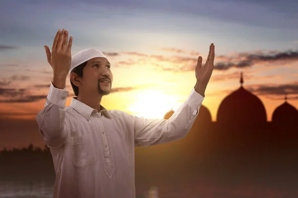 亚洲穆斯林男子高举双手站在那里 在夕阳的天空背景下祈祷 — 图库照片
